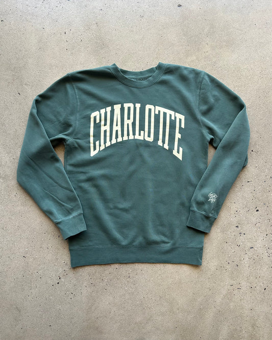 Green sweatshirt with 'Charlotte' text on a concrete surface